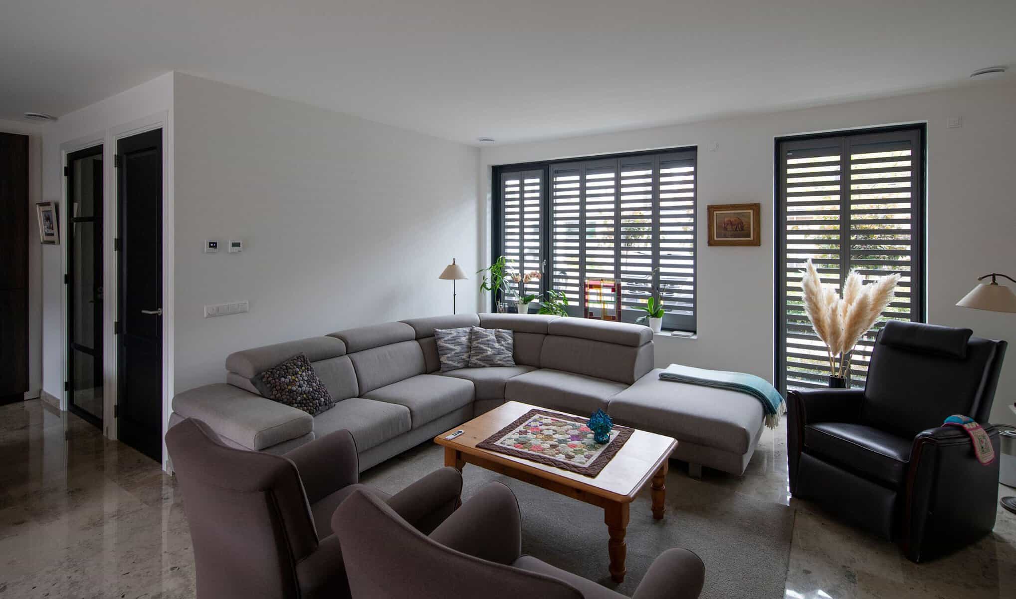 Binnen aanzicht antraciete zonnescreens in combinatie met Fractions aluminium shutters met patronen in open lichtinval stand